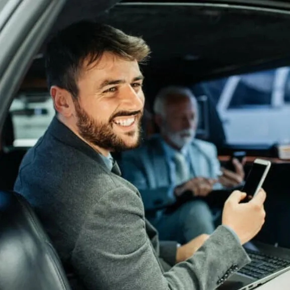 Enhance Your Corporate Image with Limo Travel for Business Events Two businessmen are working with laptops and phones inside a luxury limo for a corporate meeting.