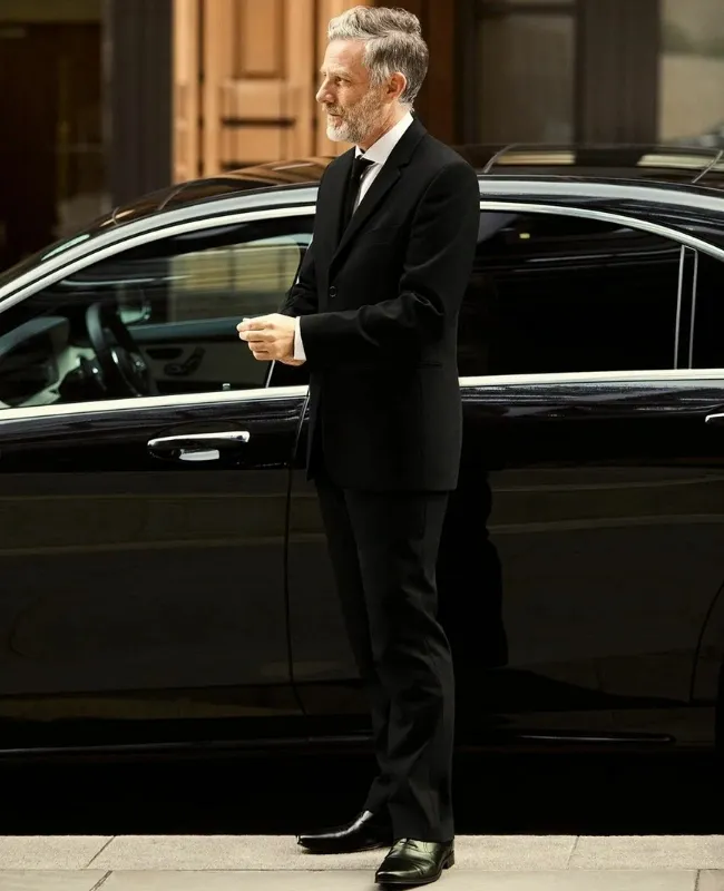 chauffeur standing with car A professional chauffeur standing with the luxury car, waiting for clients.