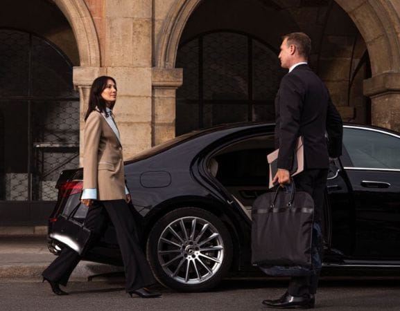 Benefits of a Private Car Service for Your Journey A Professional Chauffeur Opening CarDoor for Business Lady.