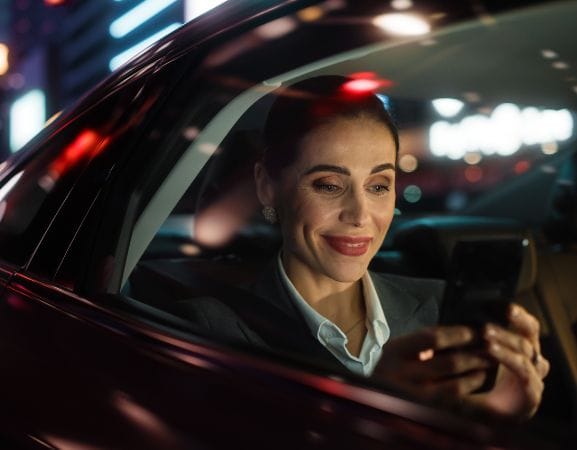 Cape Cod Car Service A business woman using mobile in luxury black car.