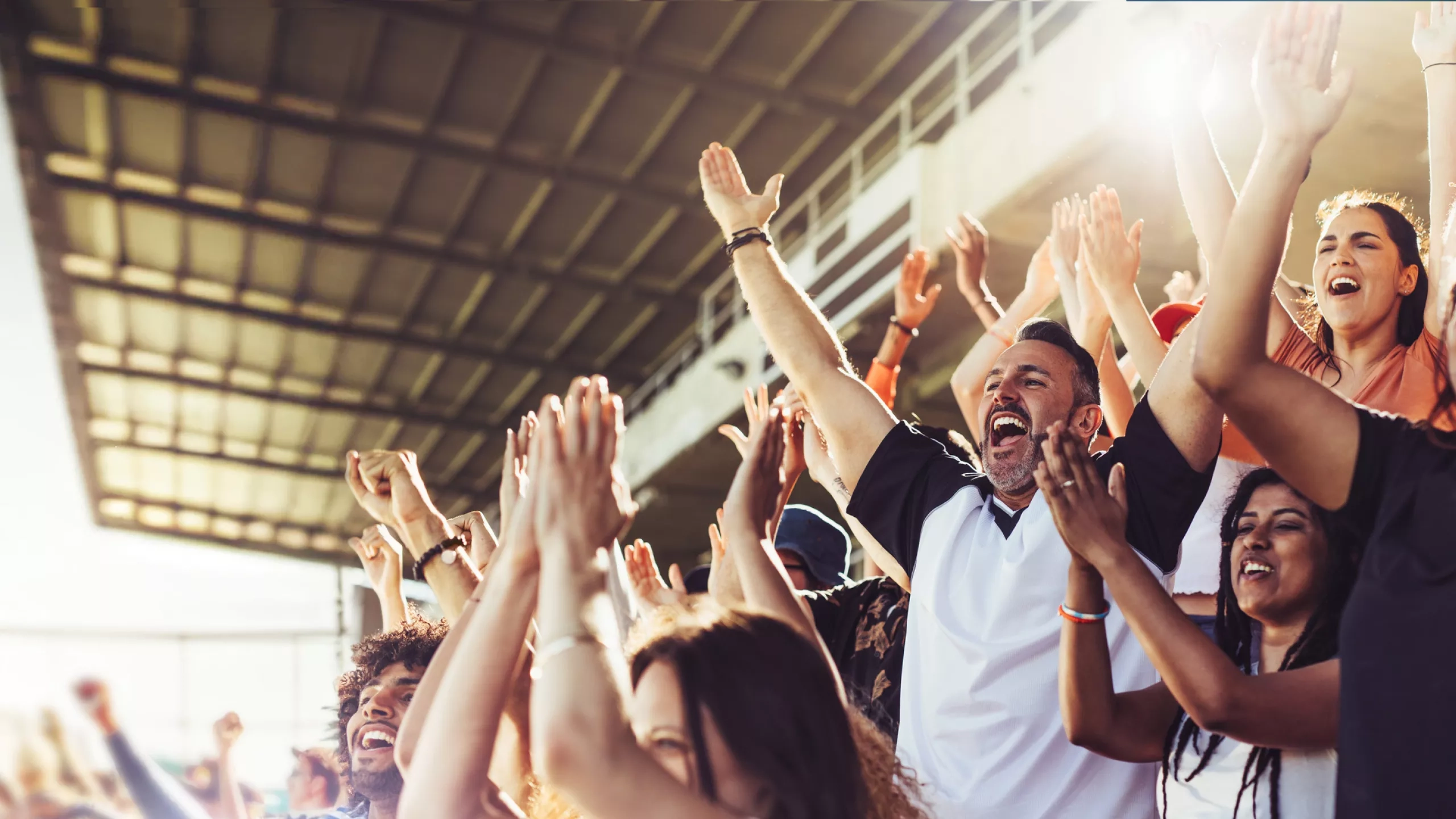 game-day-travel Excited sports fans cheering with hands raised in a stadium.