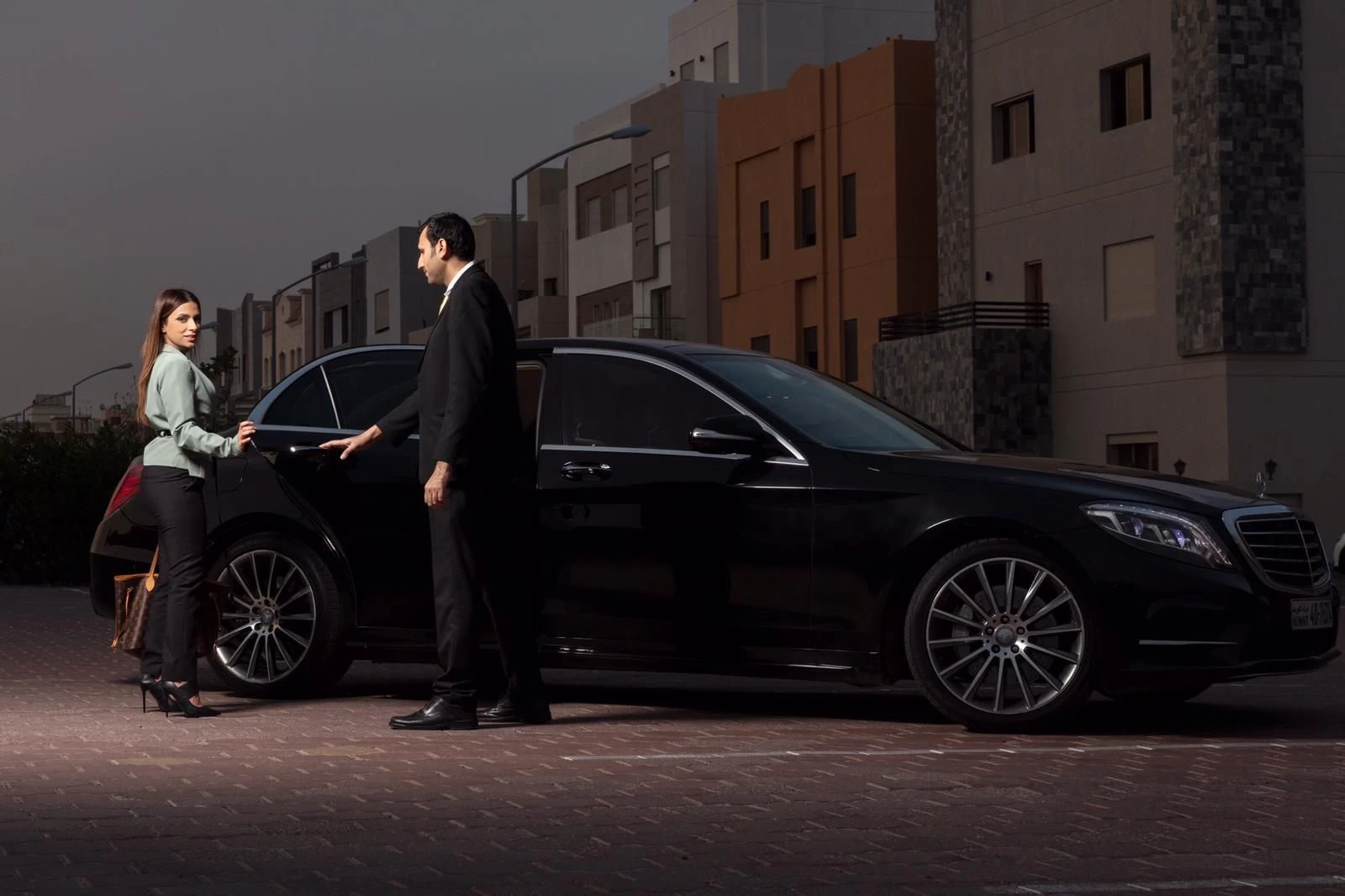 Chauffeur holding the door of a black car for a guest