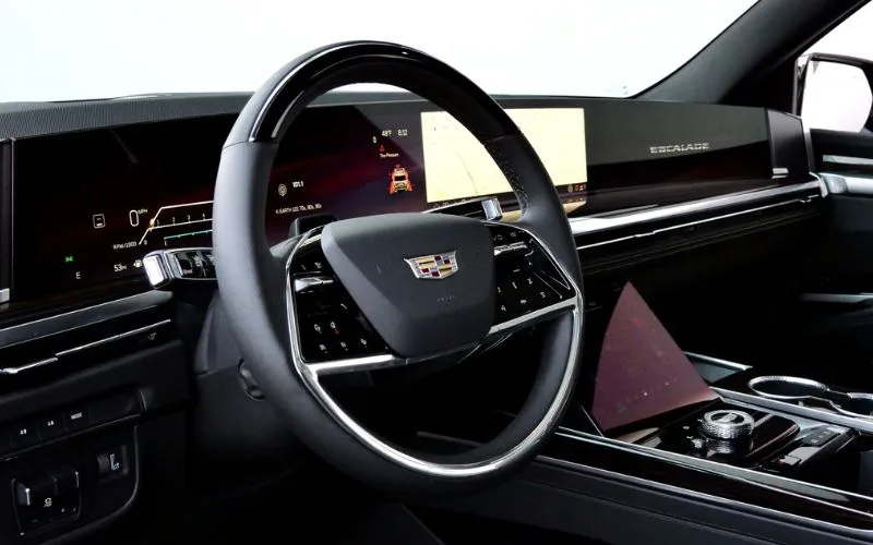 Cadillac Escalade driver's cockpit featuring a curved OLED dashboard display and leather steering wheel