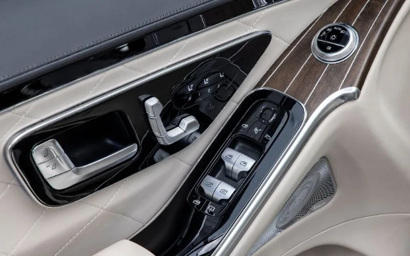 Close-up of Mercedes-Benz S-Class interior door panel with seat adjustment controls and Burmester speaker