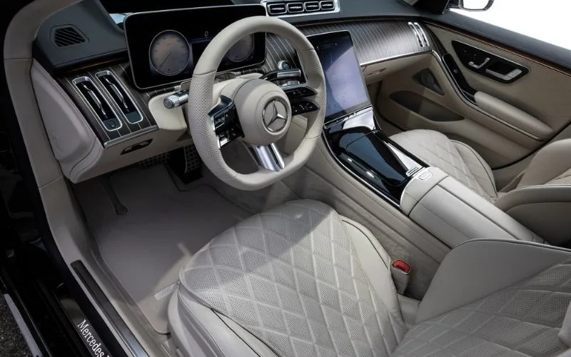 Driver's cockpit of a Mercedes-Benz S-Class featuring a digital dash and premium wood trim