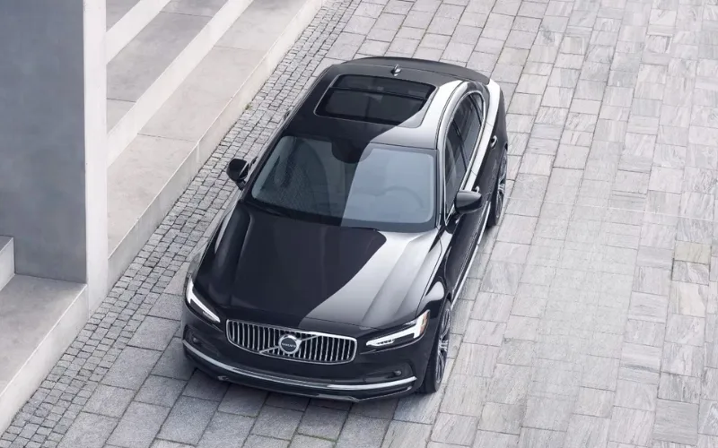 High-angle aerial view of a black Volvo S90 luxury sedan with a panoramic sunroof