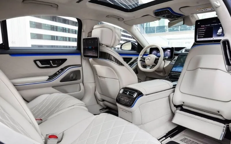 Luxury rear cabin of a Mercedes-Benz S-Class with white quilted leather and dual entertainment screens