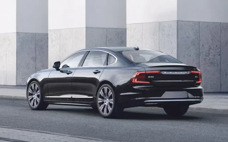 Rear three-quarter view of a black Volvo S90 luxury sedan parked on a city street.jpg