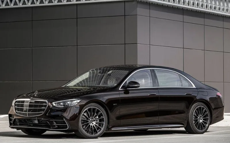 Side profile of a black Mercedes-Benz S-Class luxury sedan parked against a modern building