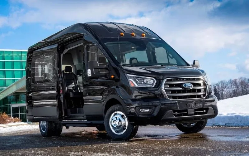 Spacious interior of a Ford Transit Van featuring forward-facing luxury seating for 13-14 passengers