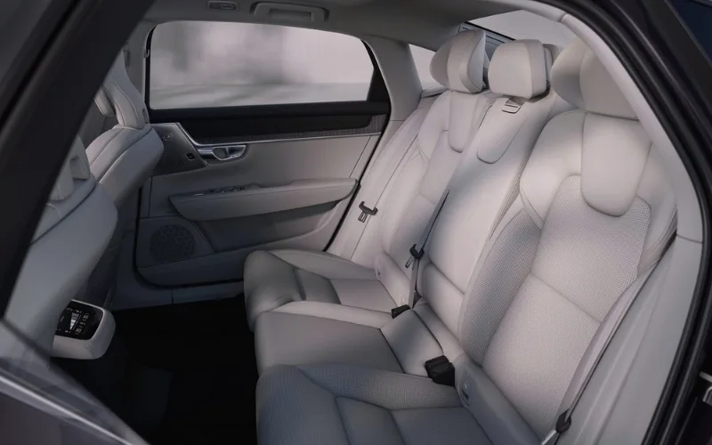 Spacious rear passenger cabin of a Volvo S90 featuring light grey perforated leather upholstery