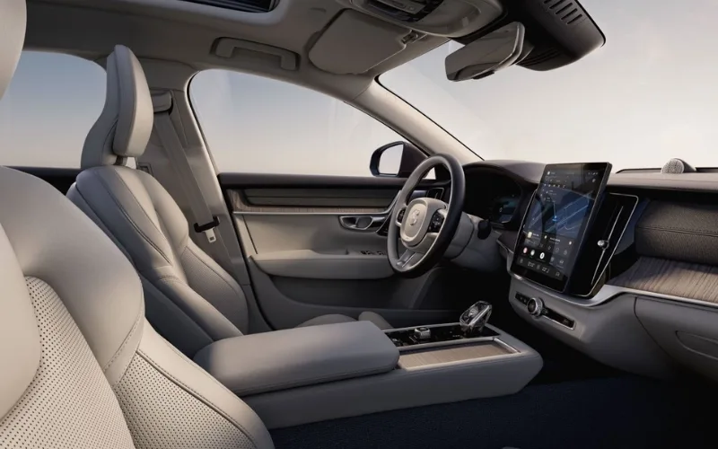Volvo S90 driver's cockpit featuring a vertical touchscreen infotainment system and wood grain trim