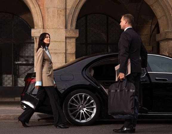 Business travelers arriving at a luxury chauffeur-driven sedan.