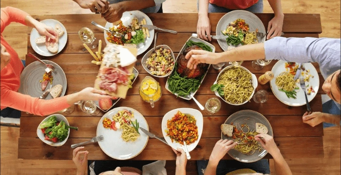 People sharing a variety of Italian dishes around a dining table during a family-style meal.