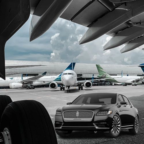 black lincoln luxury sedan parked near airplanes on the airport tarmac