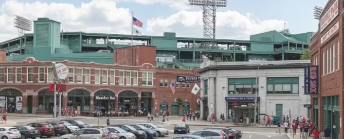 fenway park stadium overlooking parking lot with vehicles and pedestrians on sunny day