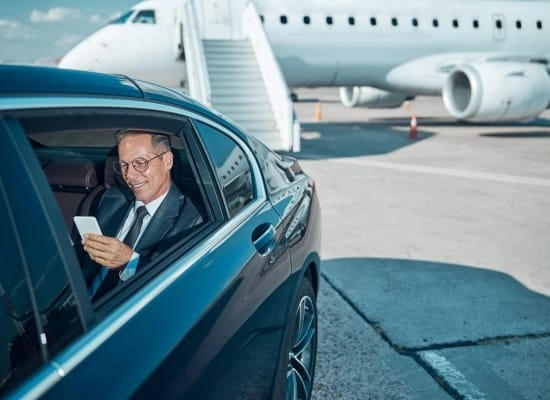 businessman using phone inside car at airport Businessman using his phone in the back of a chauffeured car at the airport
