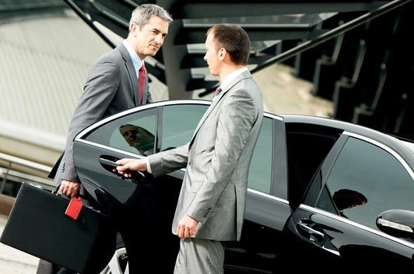 chauffeur opening black car door for businessman holding briefcase in natick ma Chauffeur opening the door of a black car for a businessman with a briefcase in Natick MA